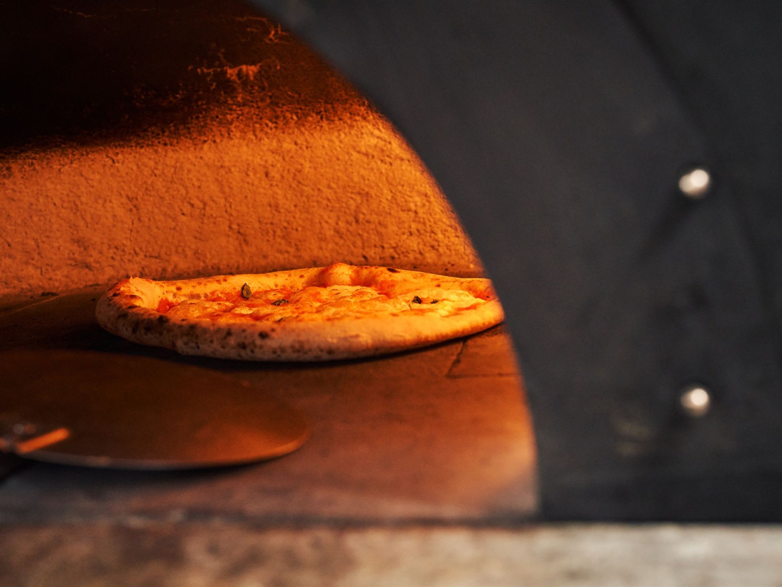 Una pizza cuoce nel calore di un forno a legna tradizionale